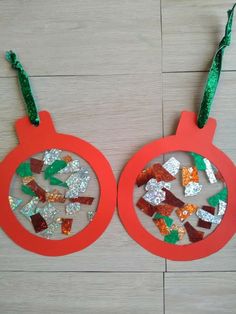 two christmas ornaments made out of paper and colored glitters on top of a wooden floor