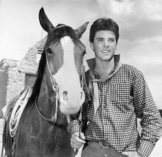 a young man standing next to a horse