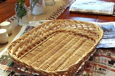 a wicker basket sitting on top of a wooden table next to magazines and vases