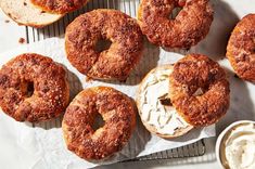 several donuts with cream cheese are on a cooling rack next to some dipping sauces