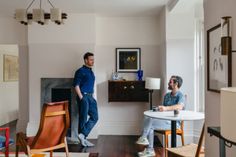 a man and woman sitting at a table in a living room with wood flooring