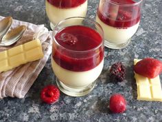 three glasses of raspberry cheesecake pudding on a granite table with two spoons