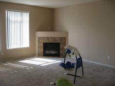 an empty living room with a fireplace in the corner