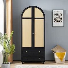 a black and white cabinet sitting on top of a floor next to a potted plant