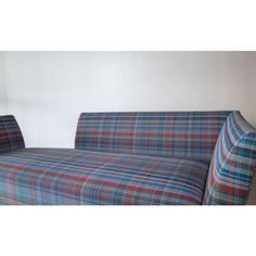 a plaid couch sitting in front of a white wall