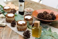 pine cones and candles on a table with leaves, wine bottle and other items in the background