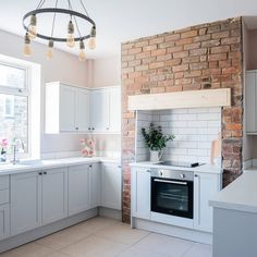 a kitchen with white cabinets and a brick wall behind the stove top oven is shown