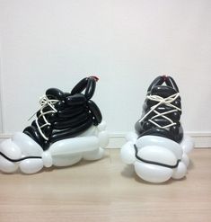 two black and white sneakers with laces on them sitting next to each other in front of a wall