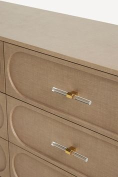 a beige dresser with three drawers and gold handles