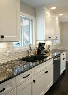 a kitchen with marble counter tops and white cabinets