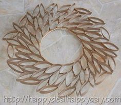 a wreath made out of cardboard with leaves on the front and side, sitting on a tile floor