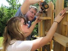 two people are building a wooden fence together