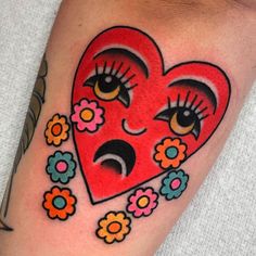 a red heart with eyes and flowers on the side of her arm, has an emo eye patch