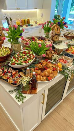 a table filled with lots of food on top of a white counter next to a window