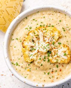 a white bowl filled with cauliflower soup and garnished with parsley