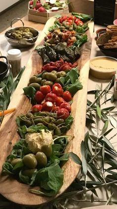 a long wooden platter filled with lots of different types of food on top of a table