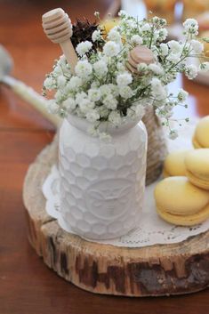 a white vase filled with flowers next to macaroons