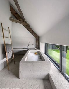 a bathtub in the middle of a room next to a window with a ladder