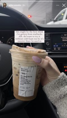 someone holding up a cup of coffee in their car