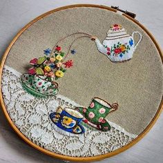 a close up of a embroidery on a piece of cloth with a tea pot and cup