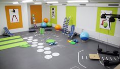 an indoor gym with various exercise equipment and yoga mats on the floor in front of colorful walls