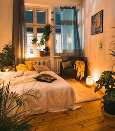 a bed sitting in a bedroom next to a window filled with potted plants and lights