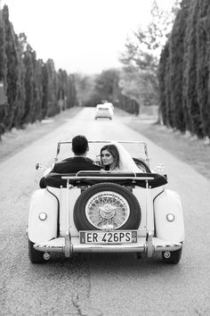 the bride and groom are riding in an old car