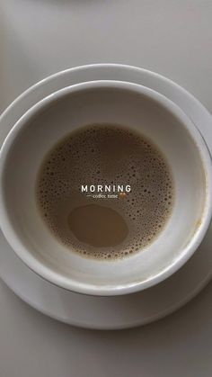 a cup of coffee sitting on top of a white plate with the word morning written in it