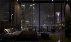 a bedroom with a large window overlooking the city at night, and it's lights are on