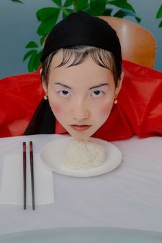 a woman is sitting at a table with rice and chopsticks in front of her