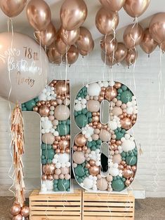 balloons and streamers decorate the letters for an 80th birthday party with gold, white, and rose gold balloons