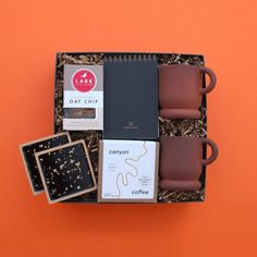 an open box with coffee, notebooks and other items in it on orange background