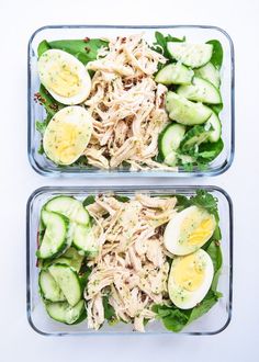 two plastic containers filled with salad and cucumbers on top of a white table