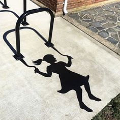 a shadow of a woman holding a tennis racquet on the ground next to a brick building