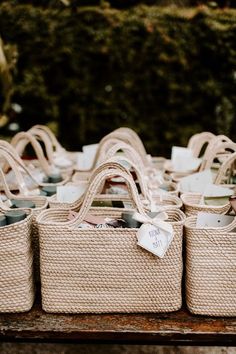 wicker baskets are lined up on top of a wooden table with tags attached to them