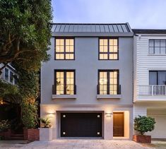 a two story house with white siding and black garage doors at dusk in san francisco, california