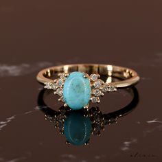 a gold ring with an oval turquoise stone and small white stones on it's side