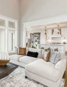 a living room filled with white furniture and lots of pillows on top of the couch