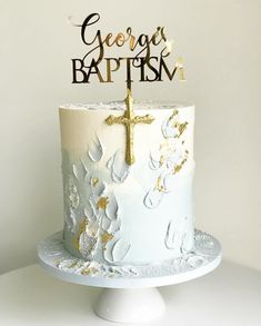 a white cake with gold decorations and a cross on top that says george baptista