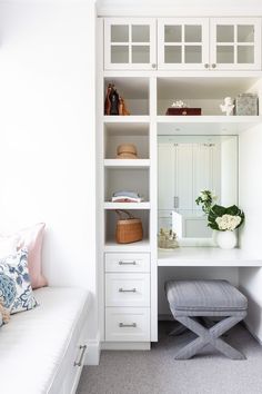 a white desk and chair in a small room with built - in shelving units