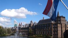 a large building with a fountain in front of it and a flag flying from the top