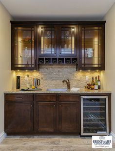 a kitchen with wooden cabinets and marble counter tops, wine bottles in the cabinet doors