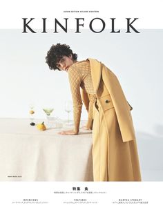 a woman leaning over a table with wine glasses and fruit on it, in front of the cover of kinfolk magazine