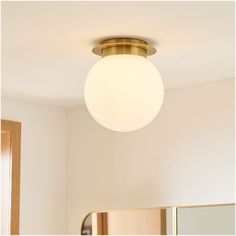 a light that is on above a mirror in a room with white walls and flooring