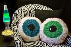 two pillows made to look like eyeballs are on a zebra print chair with the words bloodshot eyball pillow