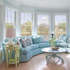 a living room filled with blue couches next to two tables and lamps on top of wooden floors