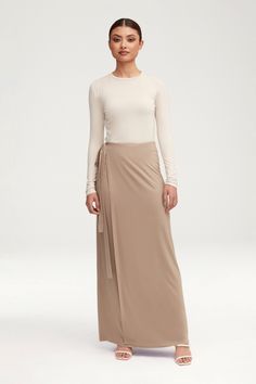 The Talia Jersey Wrap Maxi Skirt in Taupe boasts a sophisticated straight cut design with a wrap front, elevating this basic piece to a luxurious staple in your wardrobe. Crafted from high-quality jersey fabric, this maxi skirt offers comfort and style, perfect for any occasion. Model is 5'6" and is wearing size XS. Wrap Maxi Skirt, Cut Design, Straight Cut, Jersey Fabric, Maxi Skirt, Skirt, Wardrobe, High Quality, Fabric