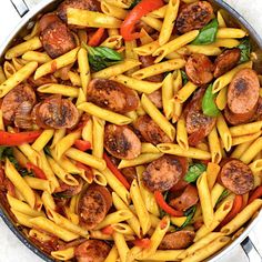 pasta with sausage and peppers in a skillet on a white table top, ready to be eaten