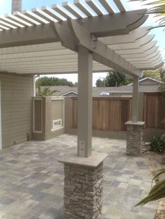 an outdoor patio with stone pillars and a pergolan roof