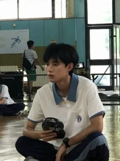 a young man sitting on the floor holding a soccer ball